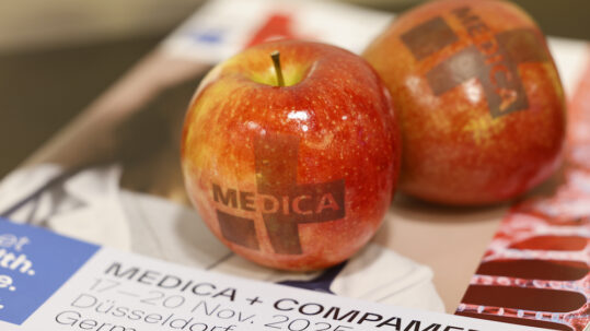 Manzanas con el logotipo de MEDICA sobre material promocional de MEDICA y COMPAMED en Düsseldorf.